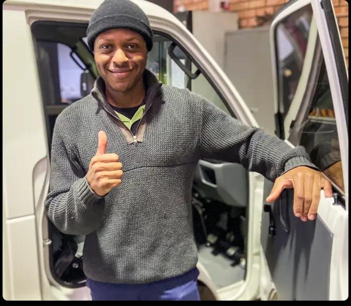 An ACCM Air Conditioning technician giving a thumbs up beside his branded service van